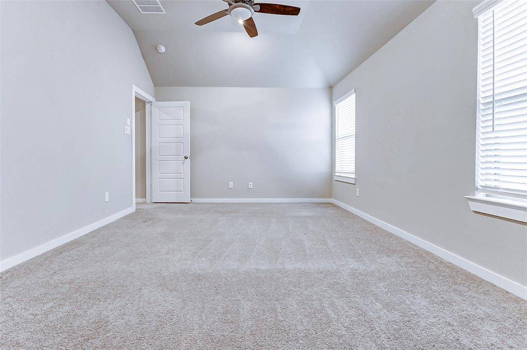 A generously sized bedroom awaits, featuring vaulted ceilings, ample natural light, and soft carpeting. It's a peaceful escape designed for rest, rejuvenation, and your favorite bedroom setup.