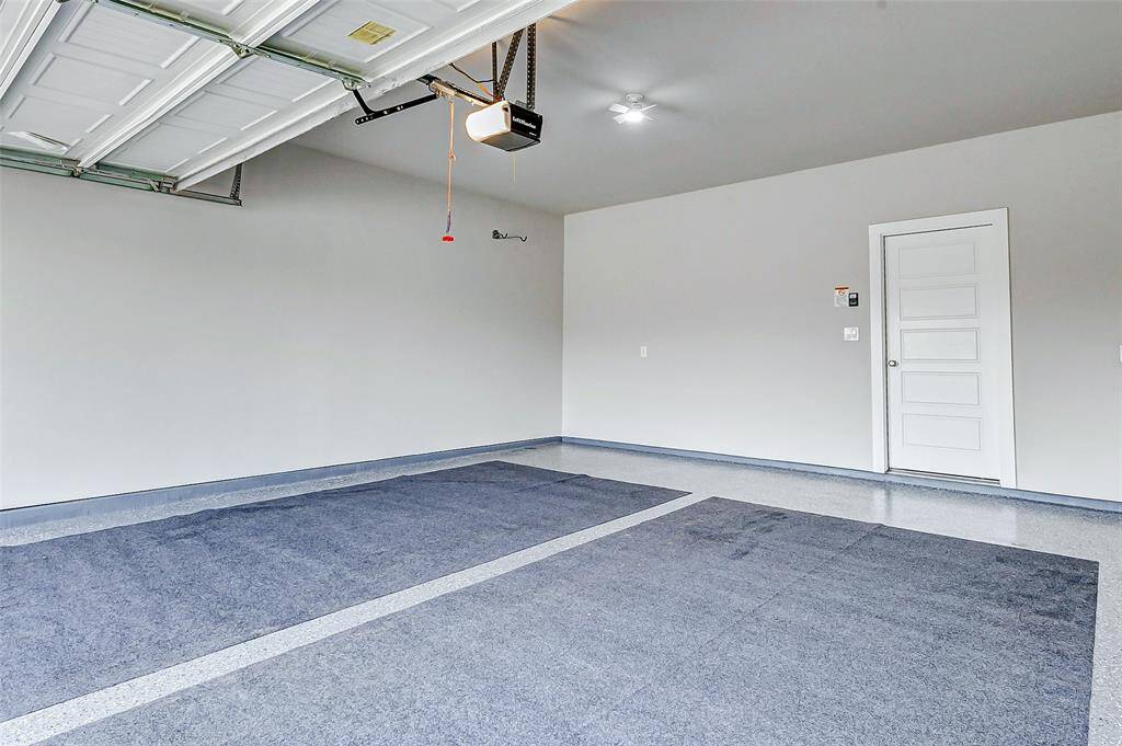 A pristine, spacious upgraded garage with epoxy flooring, updated paint on shutters and doors, offers ample storage and workspace. Perfect for vehicles or projects, this space is as functional as it is well-maintained