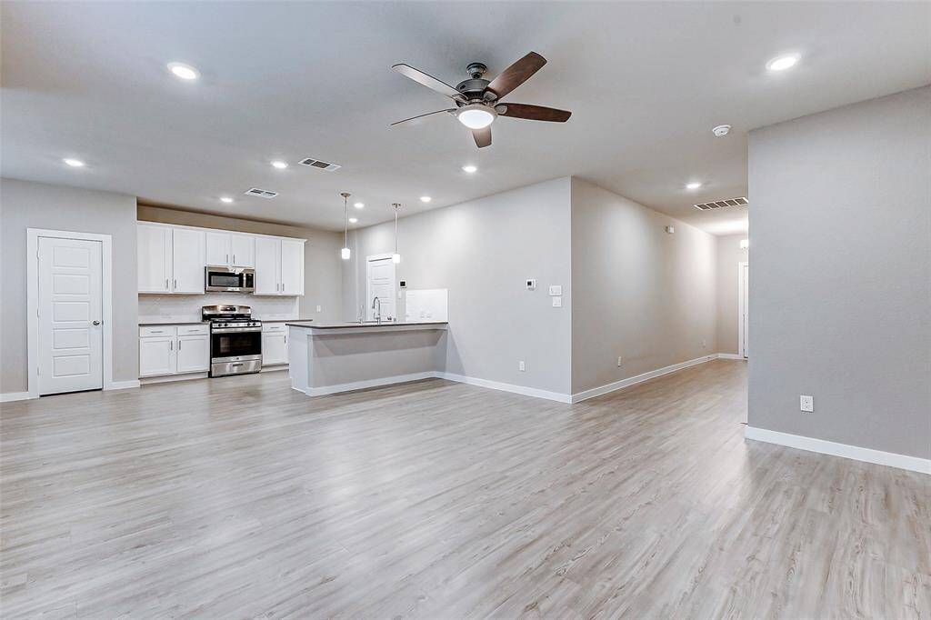 Relax in the spacious living room featuring hardwood flooring, recessed lighting, and a modern ceiling fan. The large windows flood the space with natural light, creating a warm ambiance perfect for entertaining or cozy family nights. Open to the kitchen and dining areas, this room is the heart of the home.