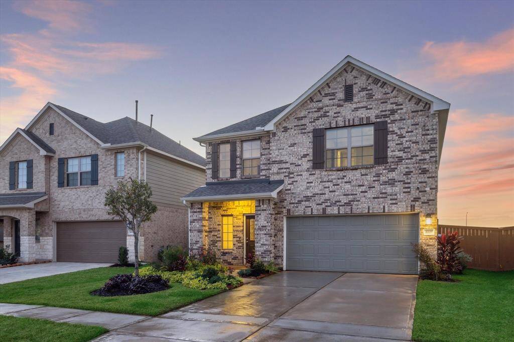 This stunning brick exterior, framed by lush landscaping, comes alive at twilight. The warm lighting highlights the inviting curb appeal, making this home a standout in the neighborhood.
