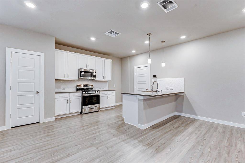 Enjoy cooking in a chef-inspired kitchen with quartz countertops, stainless steel appliances, and a stylish backsplash. The breakfast bar and pendant lighting add functionality and charm, while ample storage makes this kitchen as practical as it is beautiful.