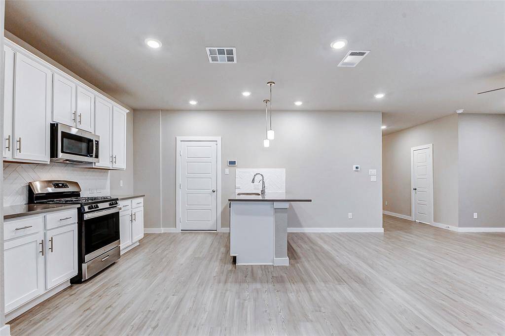 The dining area has large windows that invite natural light. Perfect for both intimate family meals and larger gatherings, the space flows effortlessly into the kitchen and outdoor patio, enhancing the overall functionality.