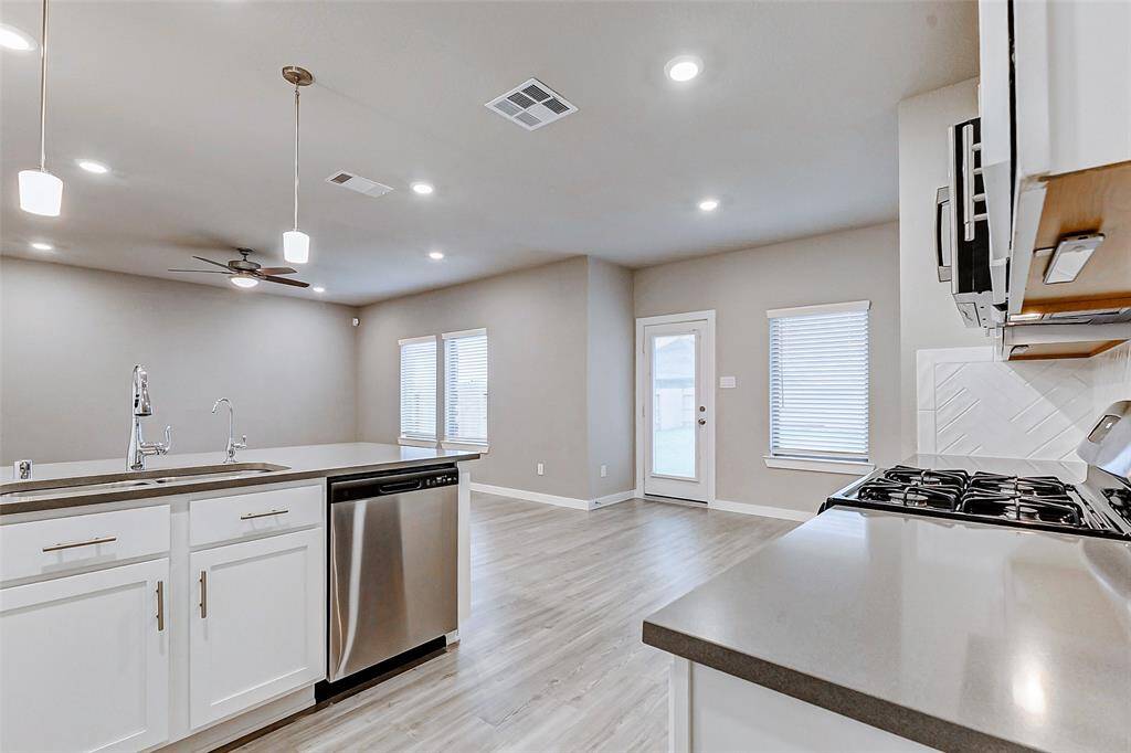 The bright kitchen boasts quartz countertops, stainless steel appliances, and a stylish herringbone tile backsplash. Pendant lighting adds a modern touch above the breakfast bar, while the dining has easy access to the backyard through a glass door. A perfect space for casual meals or formal dinners.