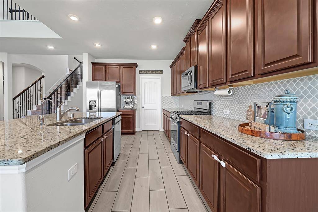 Warm Nutmeg kitchen cabinetry paired with grey clover porcelain tile backsplash and glimmering granite counters elevate your beautiful new home.