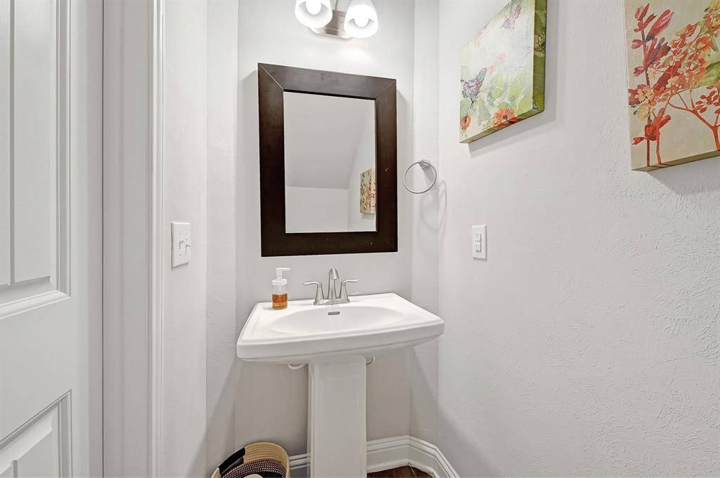 The first floor powder room is perfect for making guests feel right at home offering an elegant pedestal sink, framed mirror, and brushed nickel fixtures.