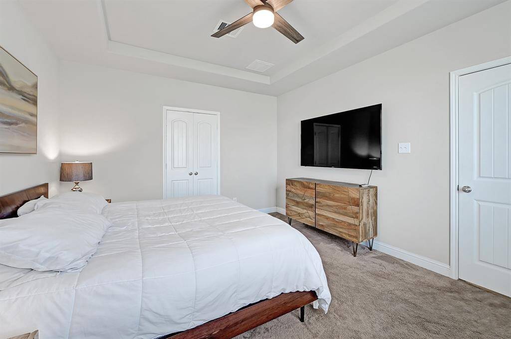 Retreat to your first floor primary suite offering plush carpeting, soaring tray ceiling, modern ceiling fan with light, and ensuite bathroom.