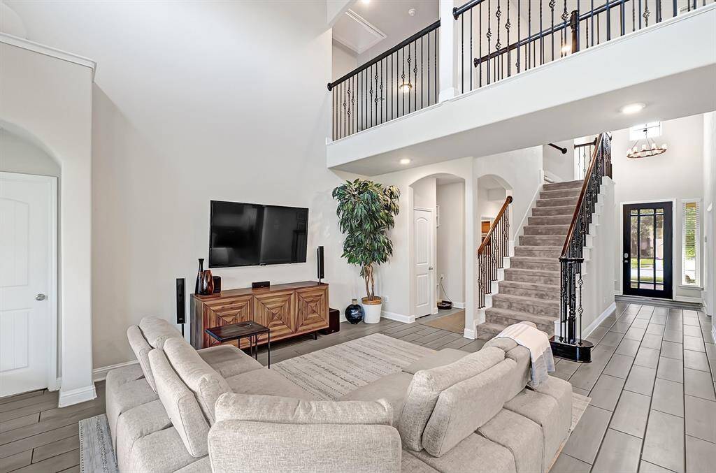The Beazer Fenway floor plan features fantastic open concept living, lofty ceilings, and elegant archways throughout. Gray wood-look tile flooring paired with neutral Agreeable Grey wall paint and crisp trim elevate your new home. Door to the left leads into the first floor primary bedroom.