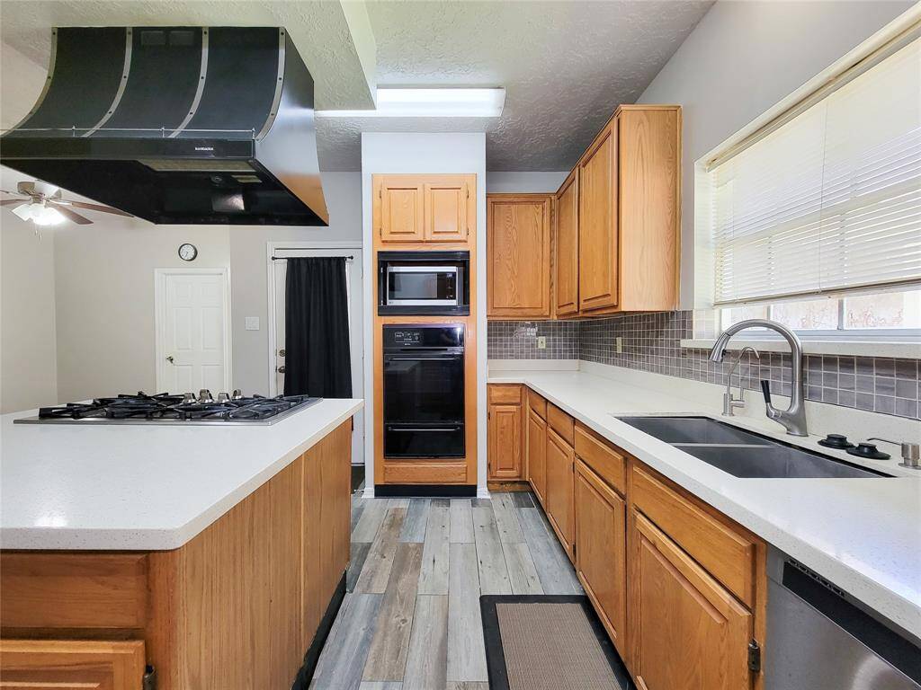 Modern kitchen featuring sleek countertops, ample cabinetry, and a stylish range hood. Perfect for culinary enthusiasts seeking functionality and elegance.