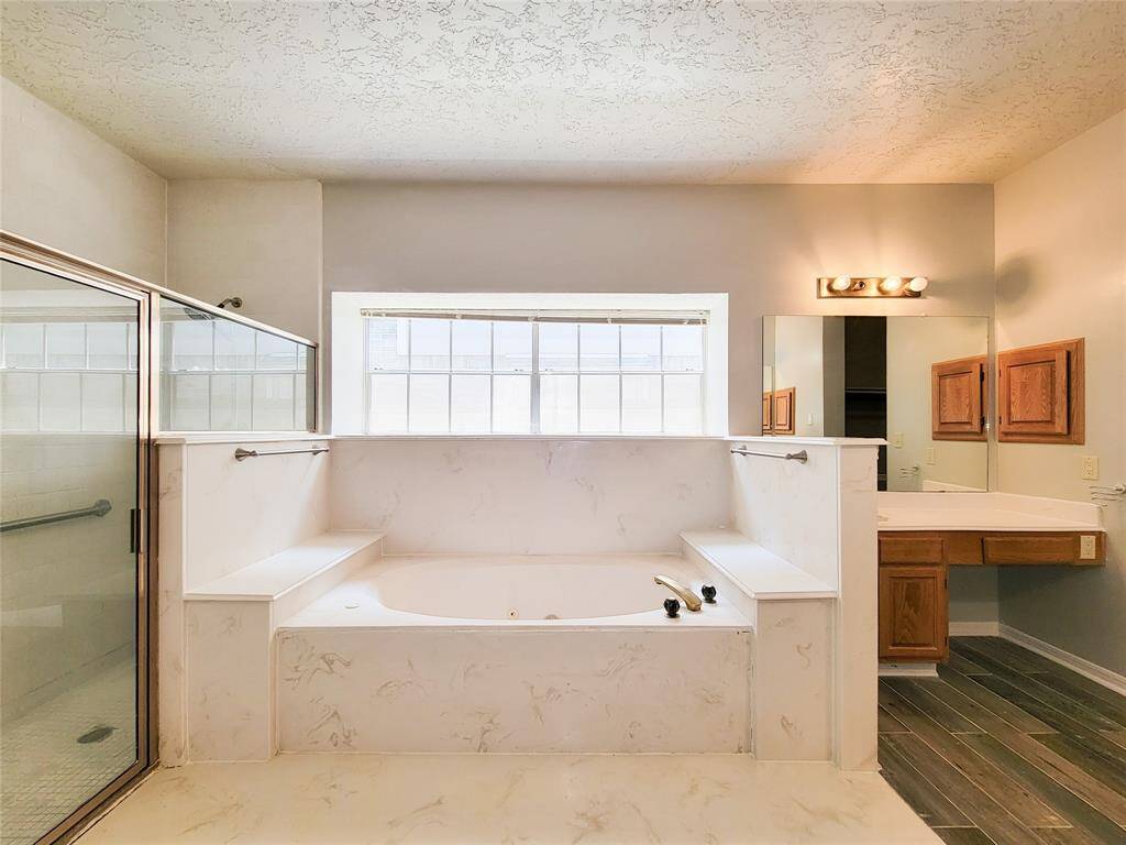 Experience ultimate relaxation in this luxurious bathroom featuring a spacious soaking tub, separate glass-enclosed shower, and elegant finishes. Natural light floods in, creating a serene oasis perfect for unwinding.