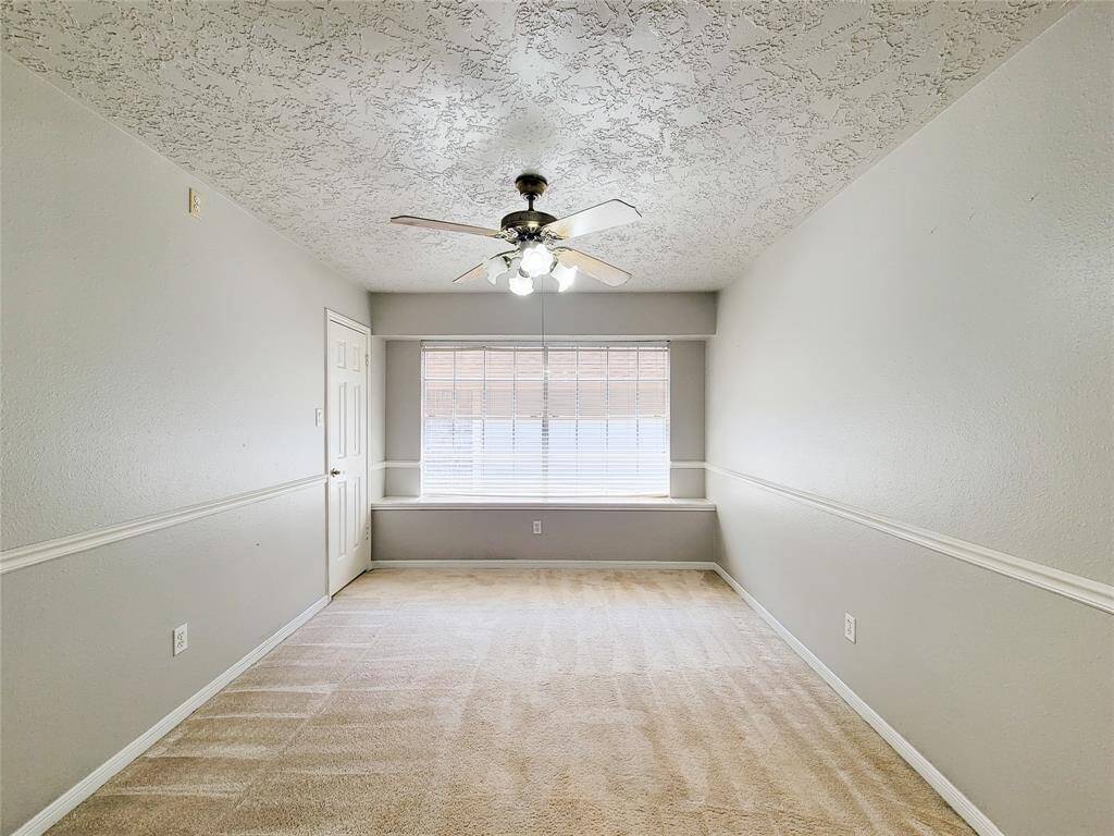 Bright and inviting room featuring a large window for natural light, textured ceiling, and a ceiling fan for comfort. Perfect for a cozy bedroom or versatile living space.