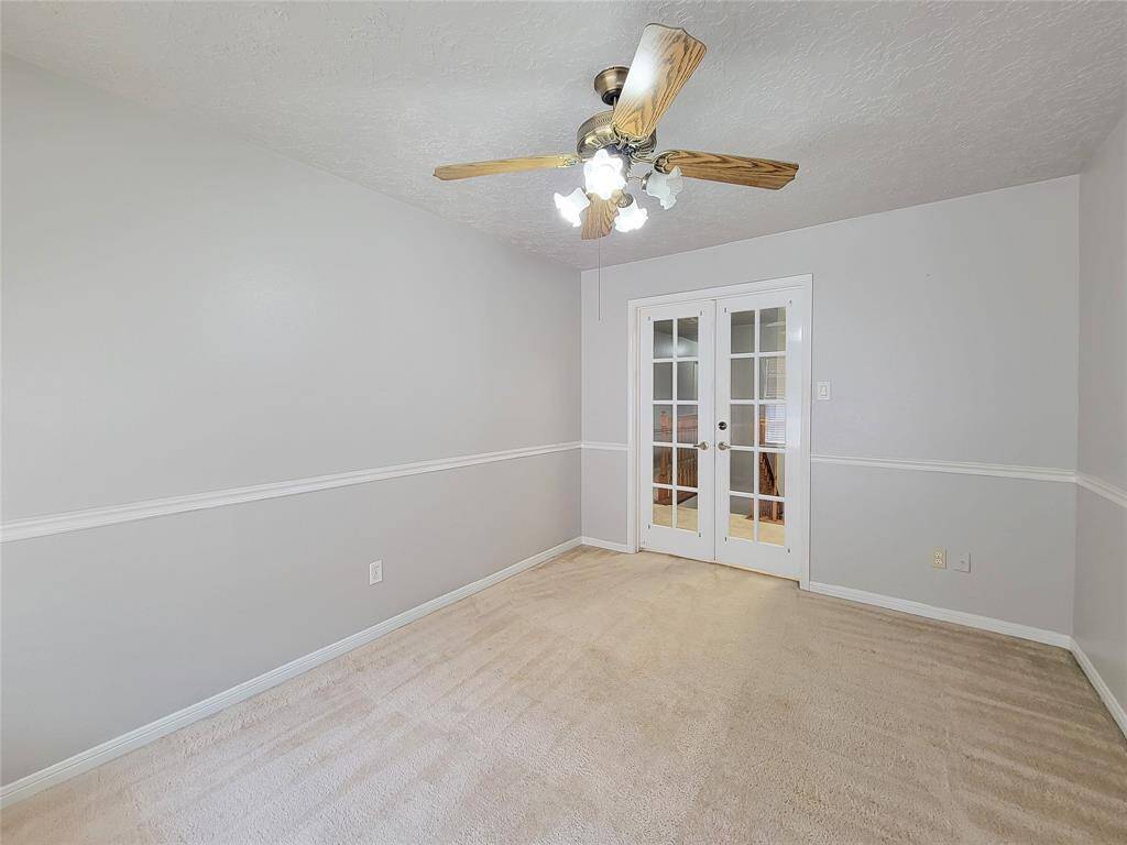 Bright and inviting room featuring elegant French doors, soft carpeting, and a stylish ceiling fan. Ideal for a cozy dining area or a versatile home office space.