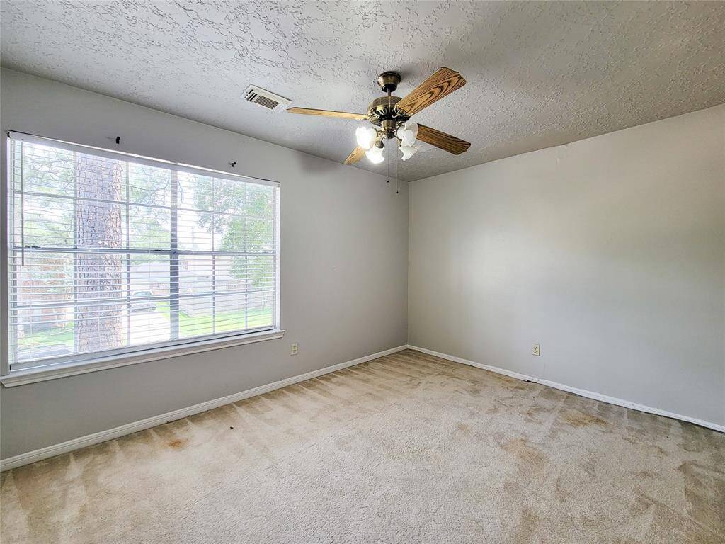 Bright and spacious bedroom featuring a large window with serene views, neutral tones, and a stylish ceiling fan, offering a perfect canvas for your personal touch.