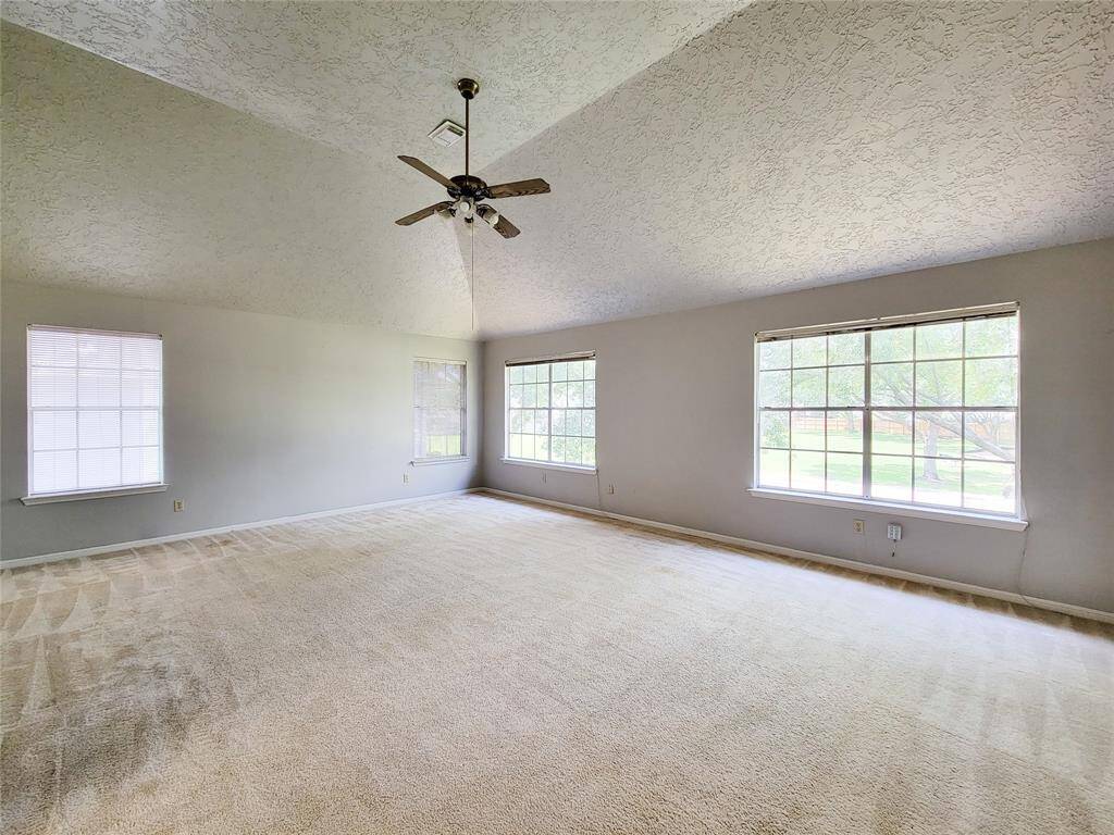 Spacious and bright room with a vaulted ceiling and large windows offering plenty of natural light. Ideal for comfortable living and entertaining.
