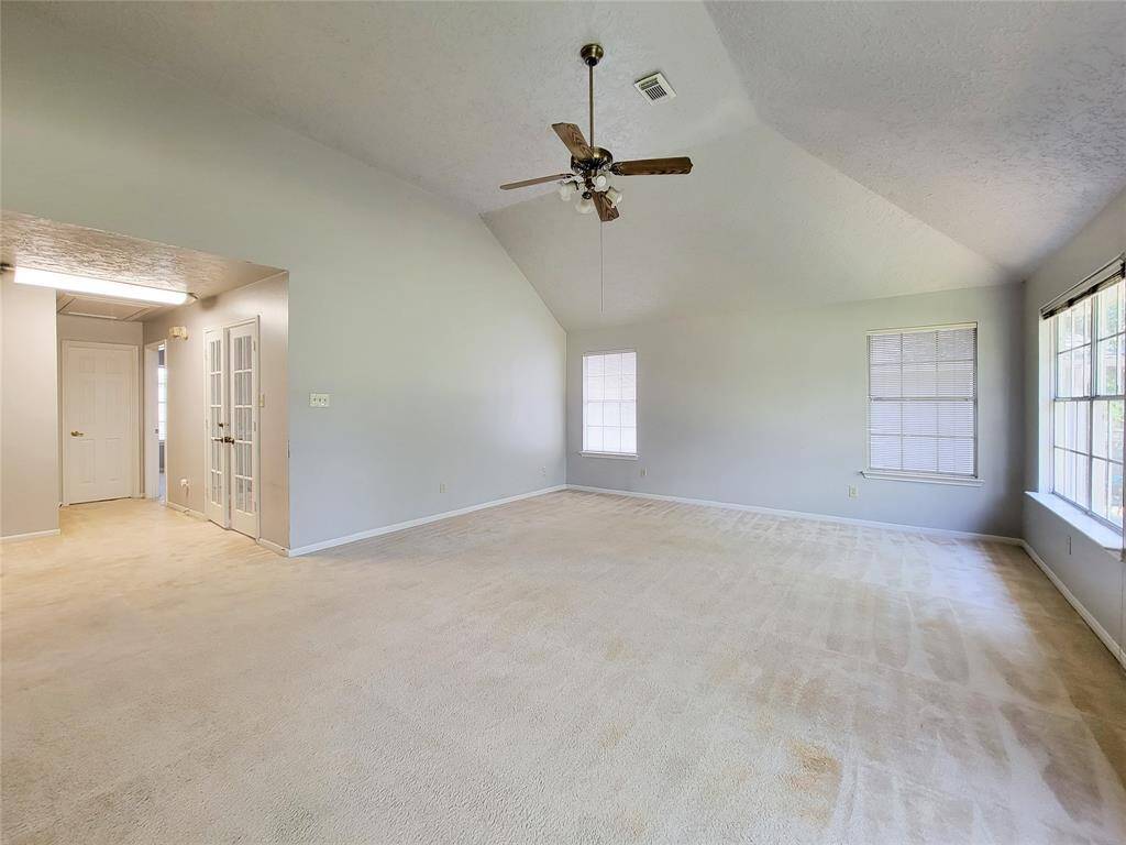 This spacious living room features high ceilings, abundant natural light, and a cozy ceiling fan. Ideal for relaxation and entertaining.