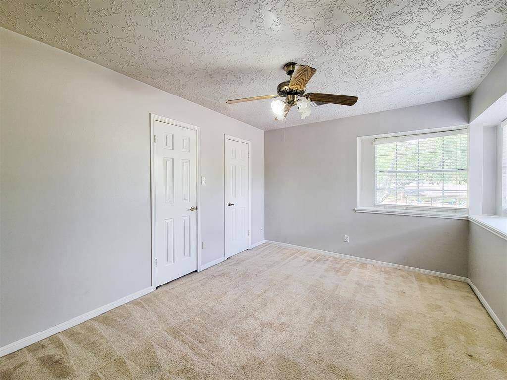 Bright and inviting bedroom featuring plush carpeting, ample natural light, and dual closets for extra storage. The stylish ceiling fan adds comfort and charm. Perfect for relaxation and rest.