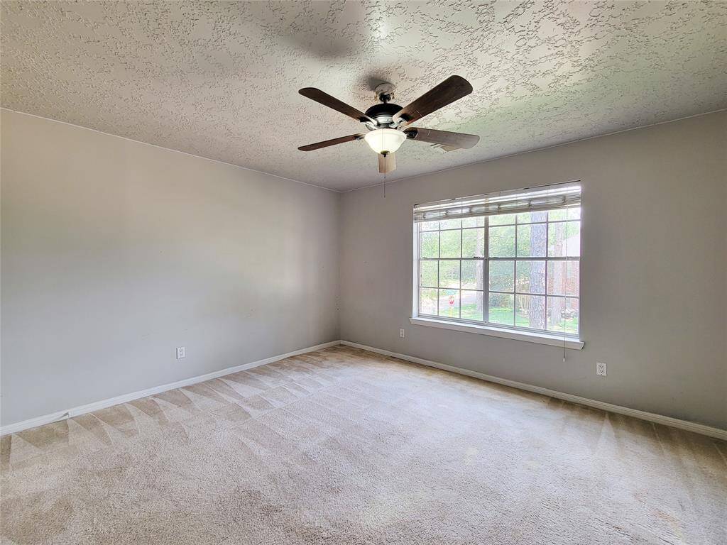 Bright and inviting bedroom with large window for natural light, neutral tones, and a stylish ceiling fan. Perfect for personalization and relaxation.