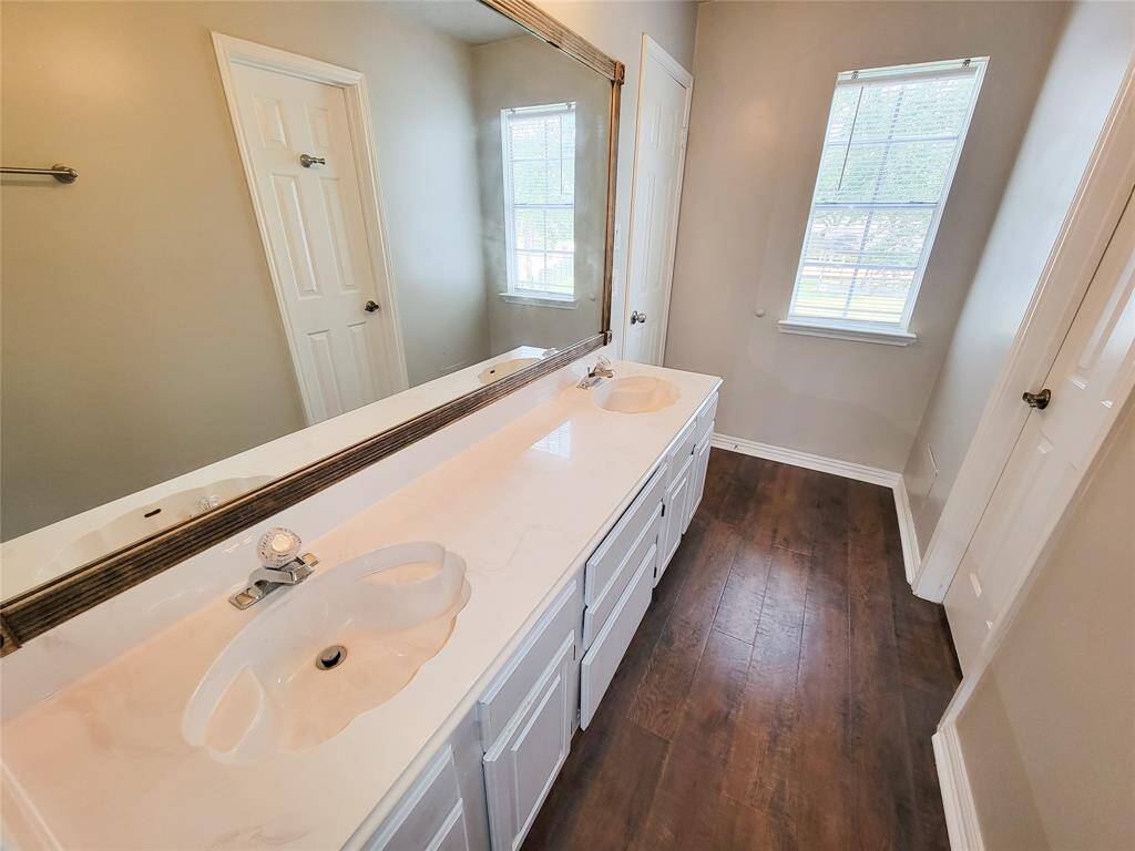 Discover this beautifully designed bathroom featuring dual sinks, a sleek large mirror, and elegant flooring, offering style and functionality.