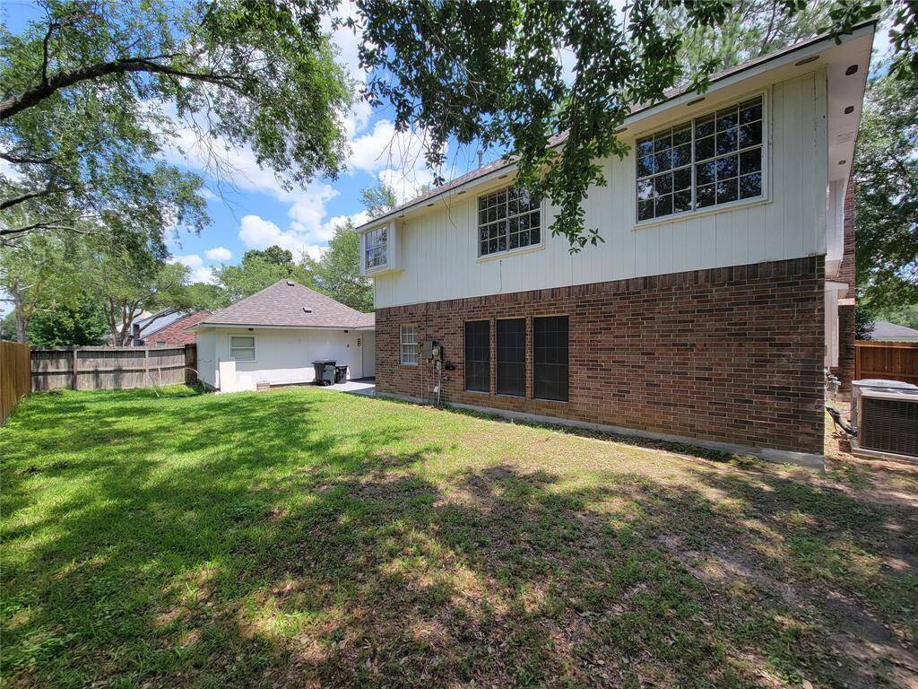 Spacious backyard perfect for outdoor relaxation and entertainment, surrounded by mature trees providing ample shade. The charming brick exterior offers a classic look, while large windows invite natural light inside. Ideal for families looking for a serene and welcoming environment.