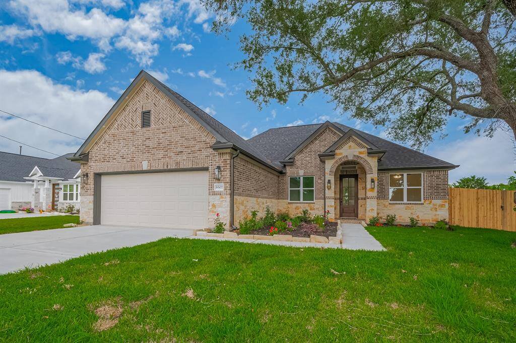This is a charming single-story brick home with a gabled roof and a spacious two-car garage. It features a welcoming front entrance framed by stone accents, a well-maintained lawn, and a paved driveway. Perfect for comfortable suburban living.