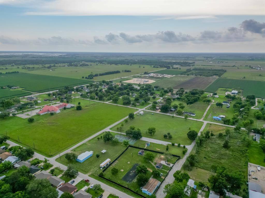 This aerial photo showcases a serene rural community with spacious green fields, scattered homes, and wide-open spaces. The area is surrounded by expansive farmland, offering a peaceful and picturesque setting ideal for those seeking a quiet, countryside lifestyle.
