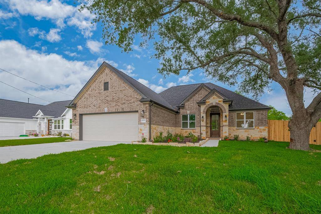 This is a charming single-story brick home with a two-car garage and a well-maintained front lawn. It features a welcoming arched entryway, large windows, and a mature tree in the front yard.