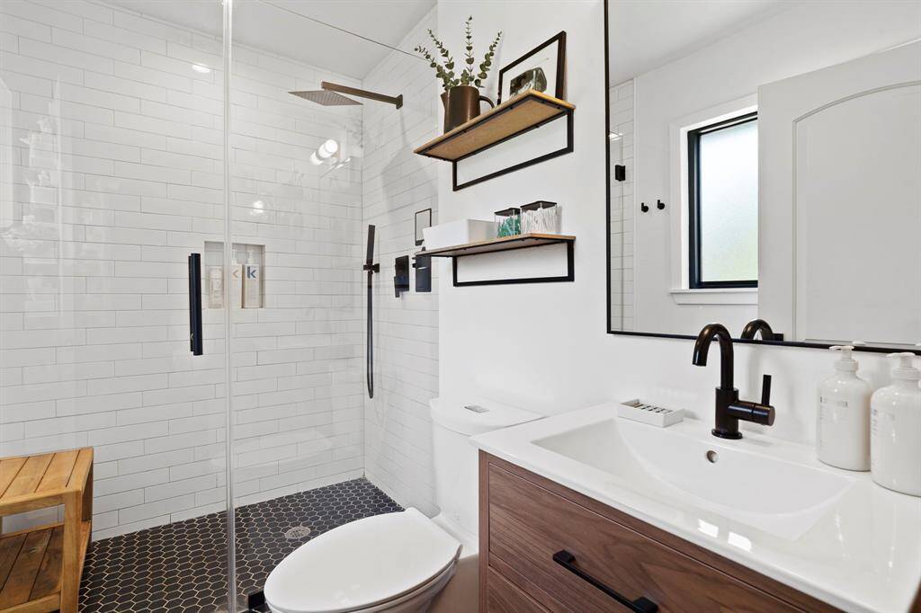 Modern primary bath completely gutted and renovated with on-trend tiling, finishes, and oversized walk-in shower, seamless glass doors.