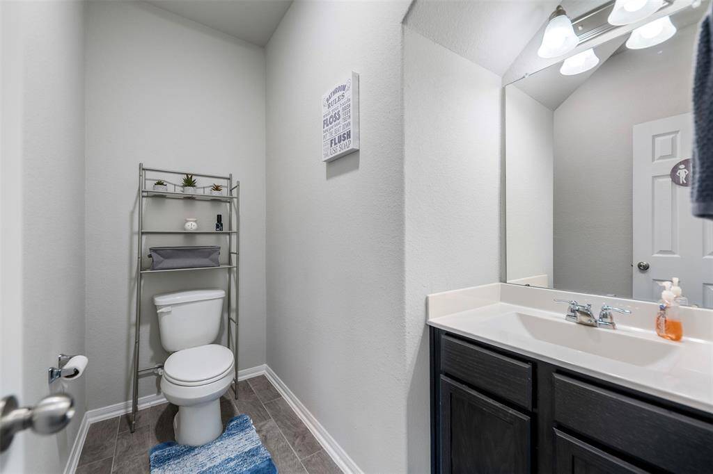 This photo shows a modern bathroom with a sleek vanity and mirror, ample lighting, and a toilet with a storage rack. The space is well-organized and features neutral tones, creating a clean and inviting atmosphere.