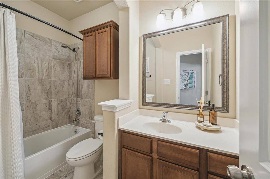 Secondary bathroom on the first floor facilitates as the guest bathroom and powder room for guests. Beautiful design with a tiled shower and bath, a large vanity with a mirror, and elegant wooden cabinetry. It offers a clean, neutral color palette and bright lighting,