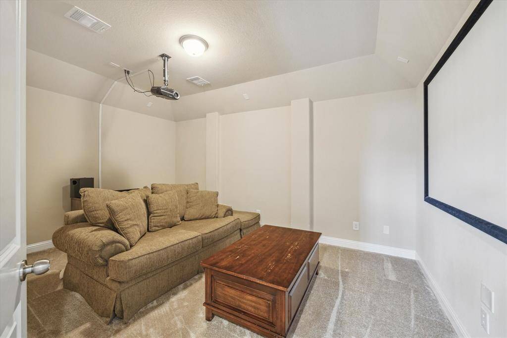 In addition to the game room, there is a cozy home theater with projector and projection screen. Ideal for movie nights. Neutral tones and carpeted flooring provide a comfortable setting.