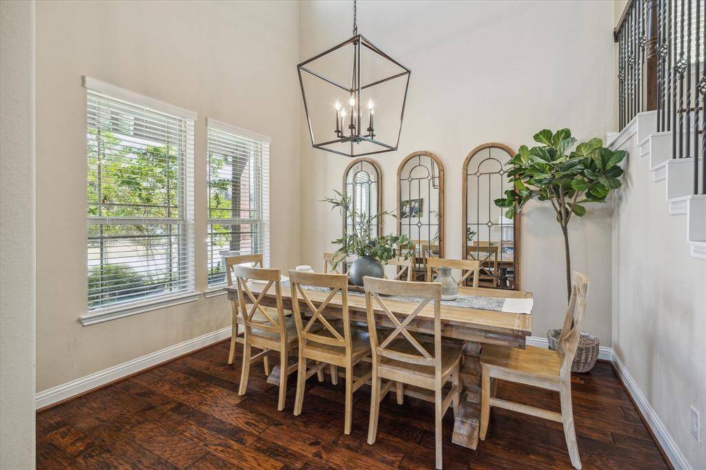 Dining area with large windows overlooking the front yard has hardwood floors, and a stylish chandelier creating an inviting space perfect for your social gatherings.