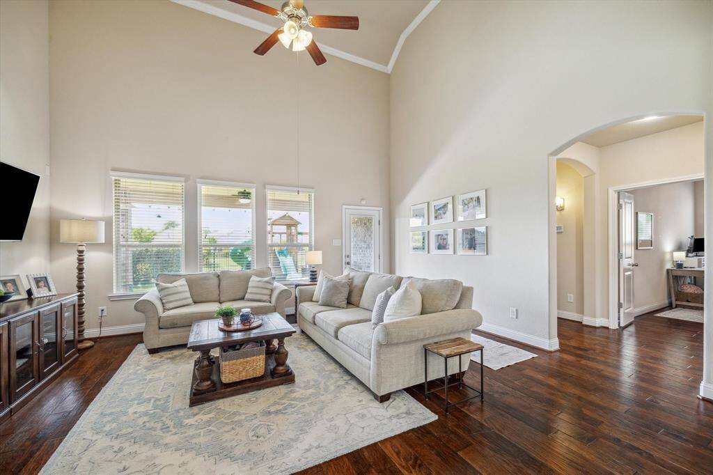 This spacious living room features high ceilings, abundant natural light from large windows, and elegant hardwood floors.