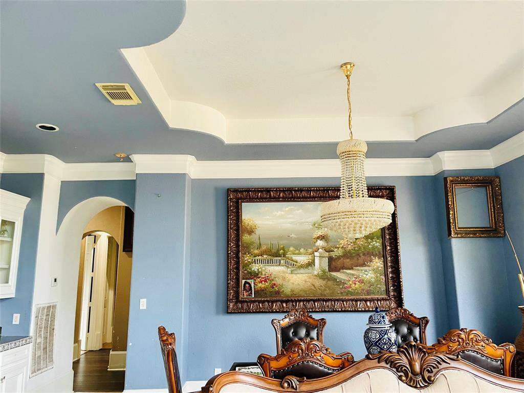 View of formal dining room from the formal living room.  Notice the details in the flooring,  moulding, tray ceiling, built-in buffet with hutch to the left