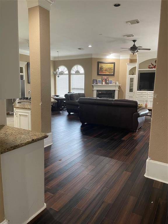 View of den from the side entrance.  Kitchen to the left.  Hardwood floors, built-in tv hutch, with fireplace and dining area to the left