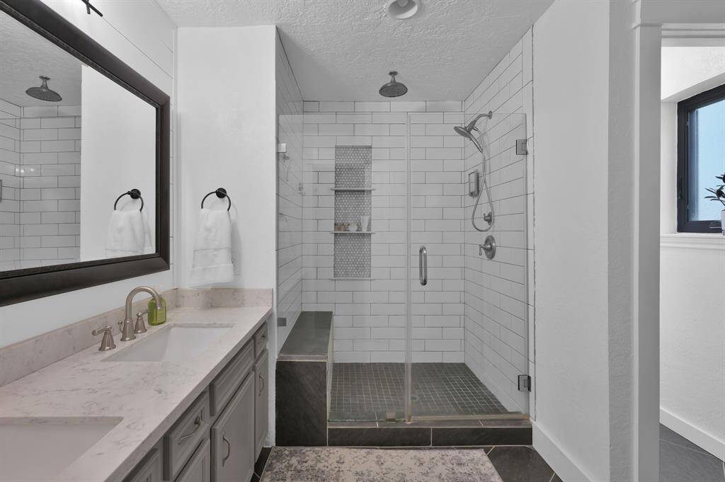 Primary bath with dual vanities and a rainfall showerhead.