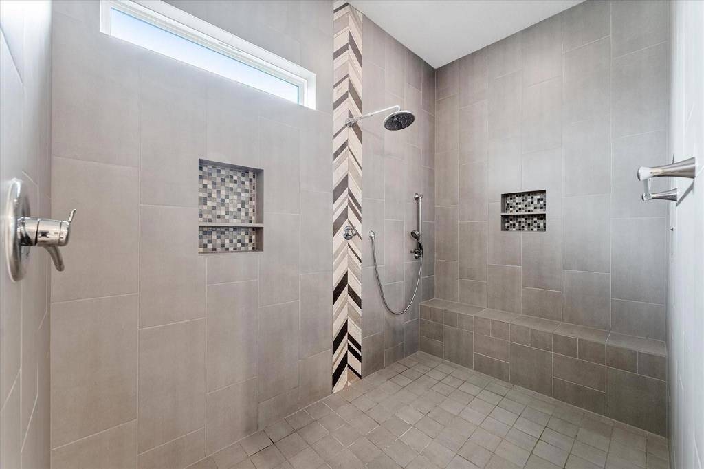 Large walk-in shower with multiple shower heads, a bench and built in tile shelves!