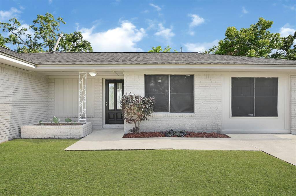 Charming single-story home with a clean white brick exterior, large windows, and a well-maintained front yard. The entrance features a decorative iron post and a small garden bed, offering great curb appeal.