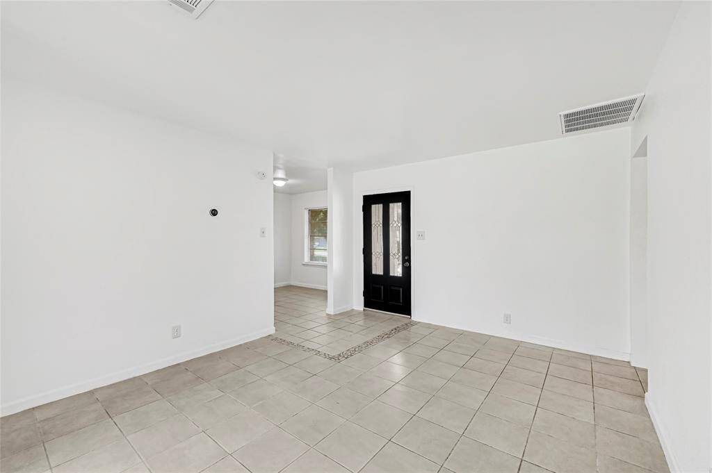 The entryway opens to the living area with natural light and the breakfast nook and kitchen area to to the right with the secondary bedrooms opposite the living area.