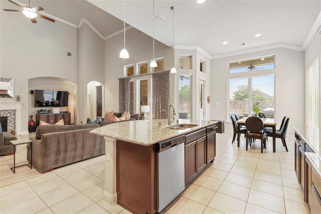 A view of the open-concept living space from the modern kitchen with an island, granite countertops, adjoining living area and breakfast area with large windows that provide plenty of natural light and views of the backyard.