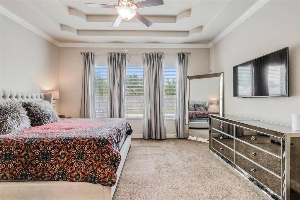 Spacious primary bedroom with a tray ceiling and large windows.