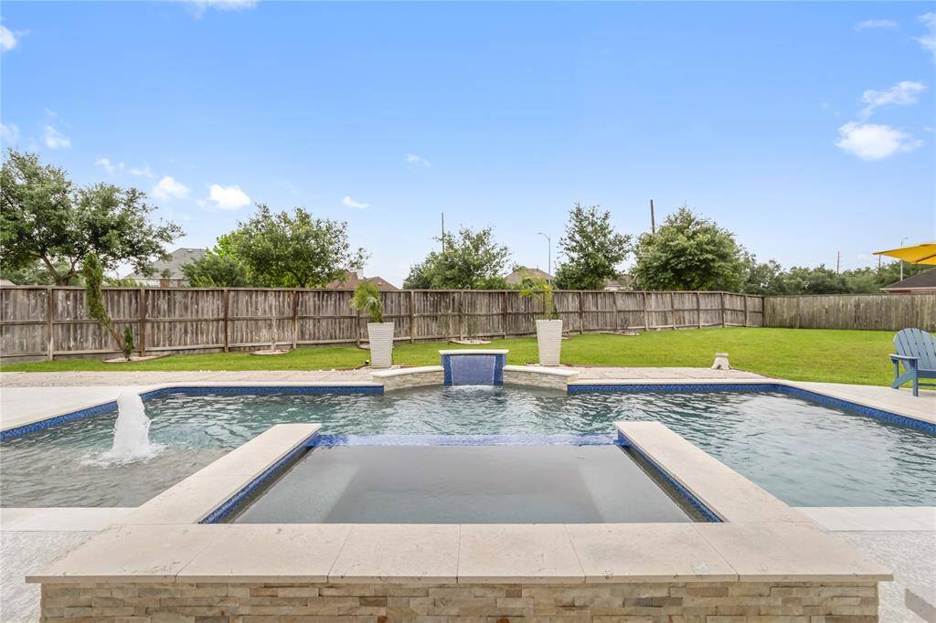A resort style backyard featuring a modern swimming pool and spa.