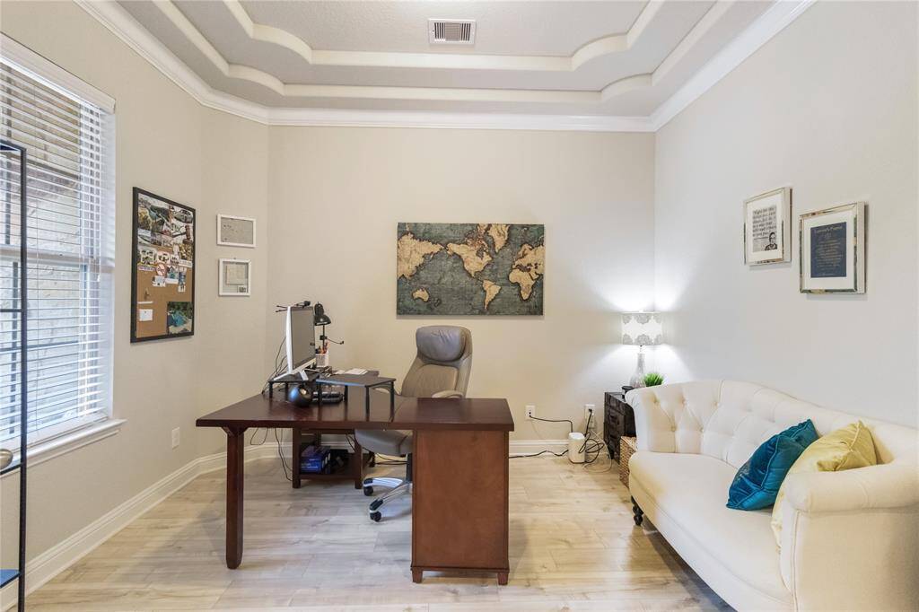 Home office with a tray ceiling is found at the entrance of the home.