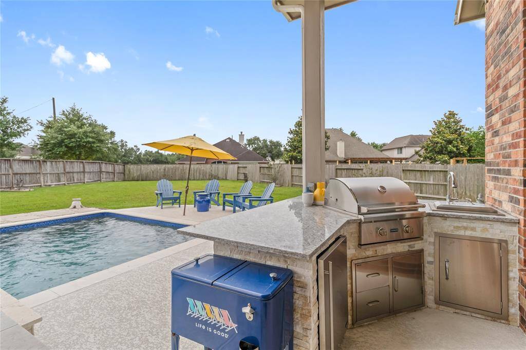 The backyard also features a modern outdoor kitchen with a built-in grill and sink.
