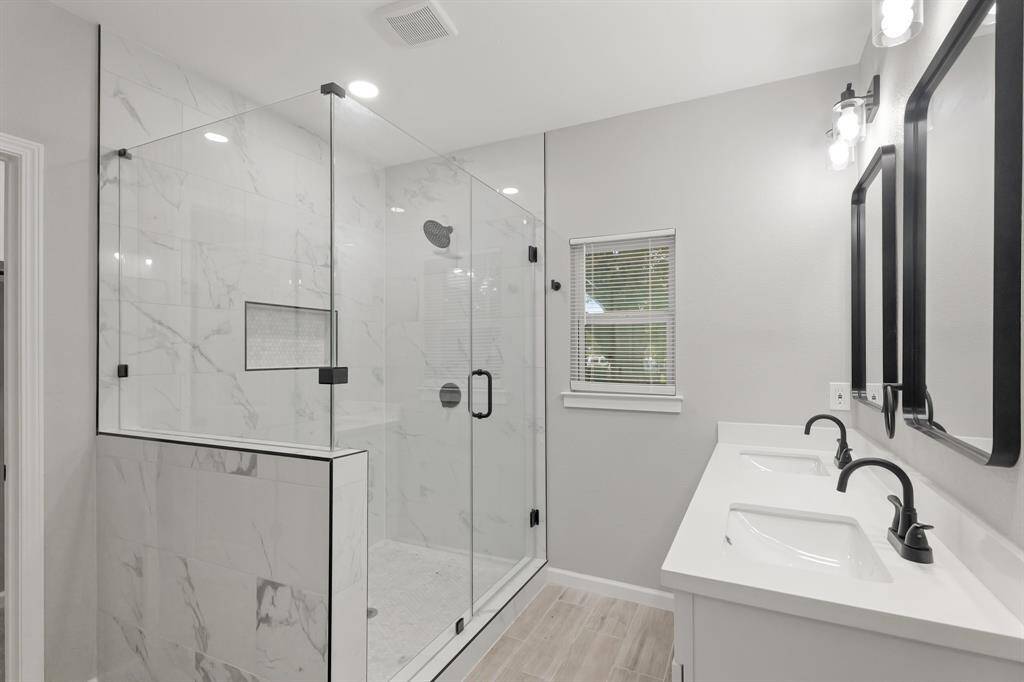 The expansive walk-in shower, adorned sleek glass front, offers a luxurious escape for a quick rinse or a refreshing retreat.