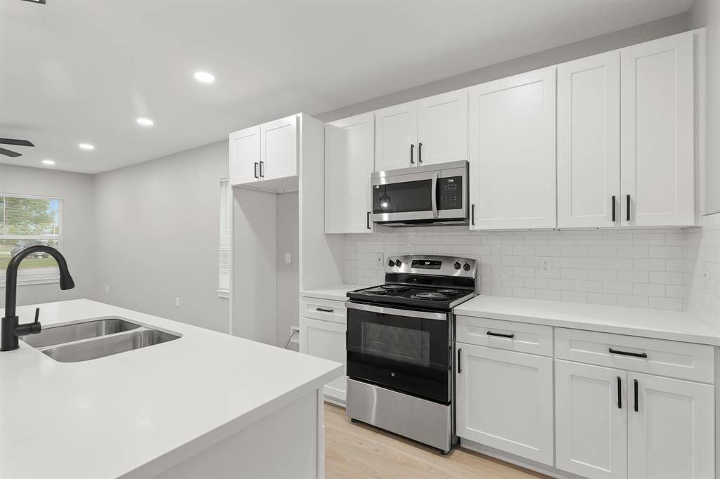 The crisp white cabinetry, enhanced with updated hardware, is perfectly complemented by recessed lighting, creating a bright and inviting ambiance.