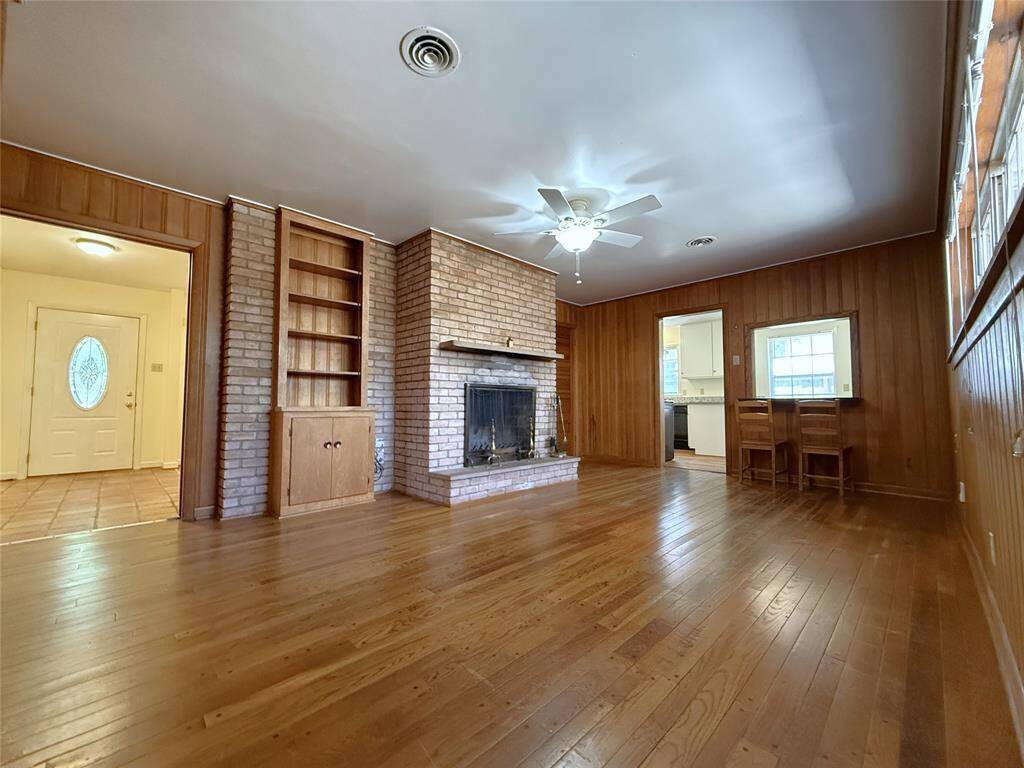 With ceiling fan, the family room offers a wood burning fireplace, built-in shelving/cabinet and beautiful vintage wood paneling.