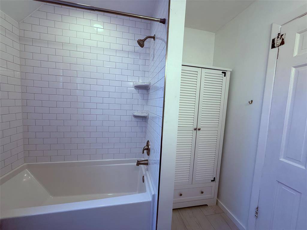 Soaking tub/shower combo and linen storage.