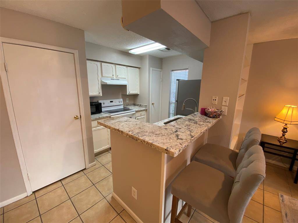 This cozy kitchen features granite countertops with a breakfast bar, tile flooring, and white cabinetry. It includes Standard size appliances.