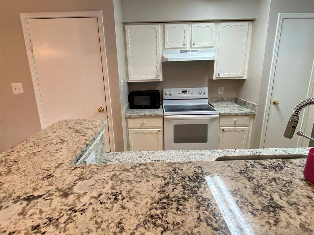This kitchen features. A microwave and a stainless steel faucet, offering a clean and functional cooking space.