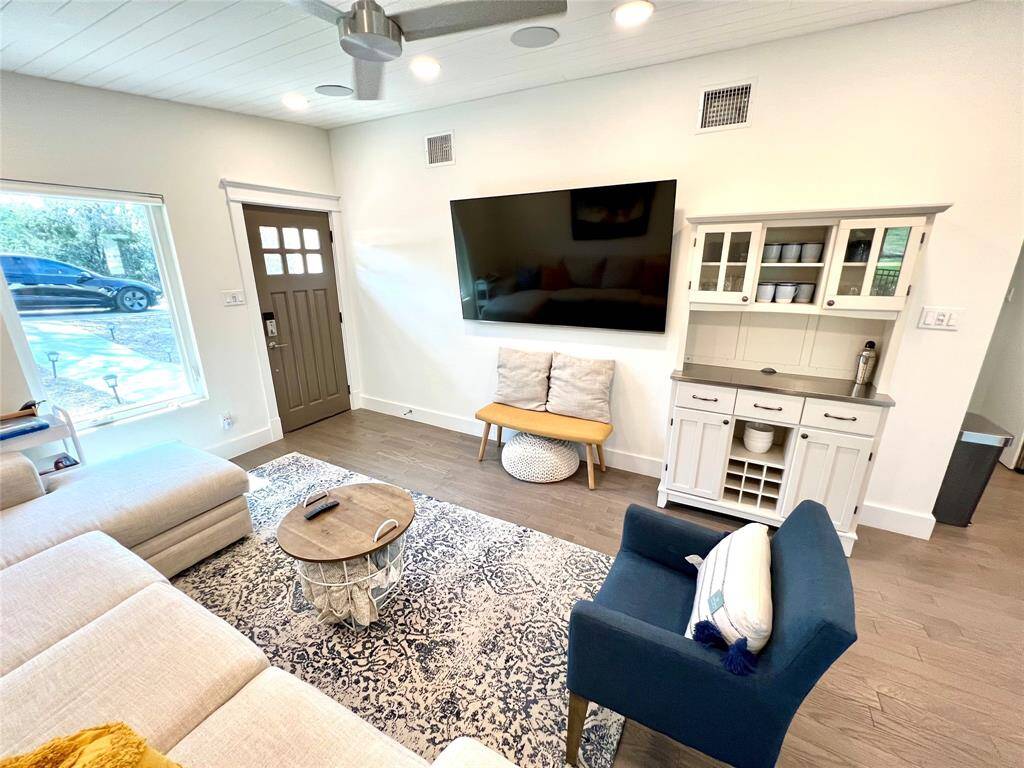 This kitchen features a modern design with sleek stainless steel appliances, white cabinetry with glass doors, and a quartz countertop. The space is bright and functional, with a cozy breakfast bar and a clean, contemporary look.