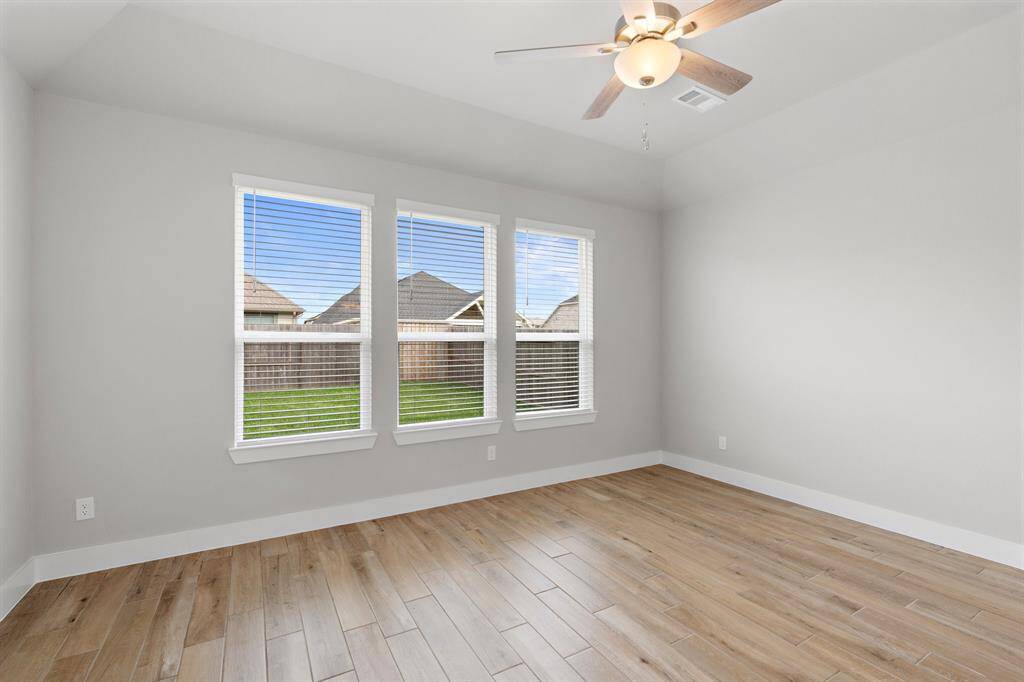 Retreat to the serene primary suite featuring a tray ceiling, ceiling fan, and three large windows that bring in natural light and views of the backyard.